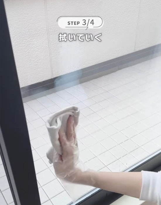 窓を布巾で拭く様子