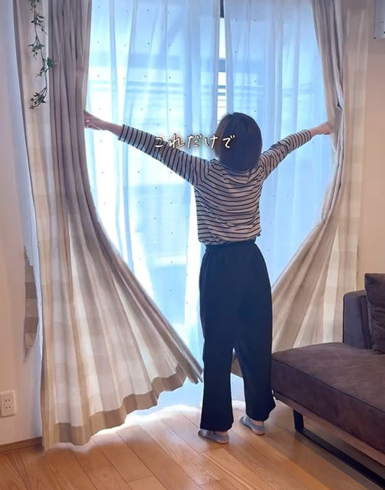 カーテンを開く女性