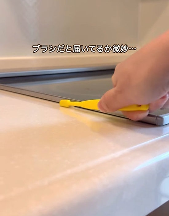 コンロの横のすき間に歯ブラシを当てる様子