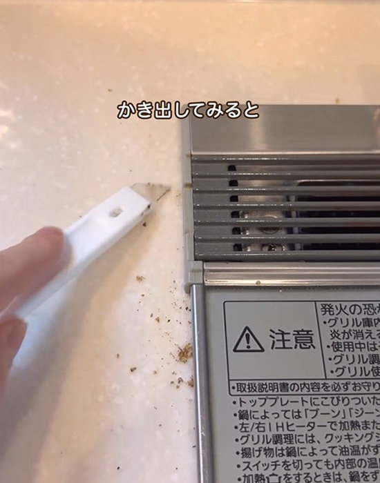 ダイソーのしなるすき間ヘラでコンロの横のすき間を掃除する様子