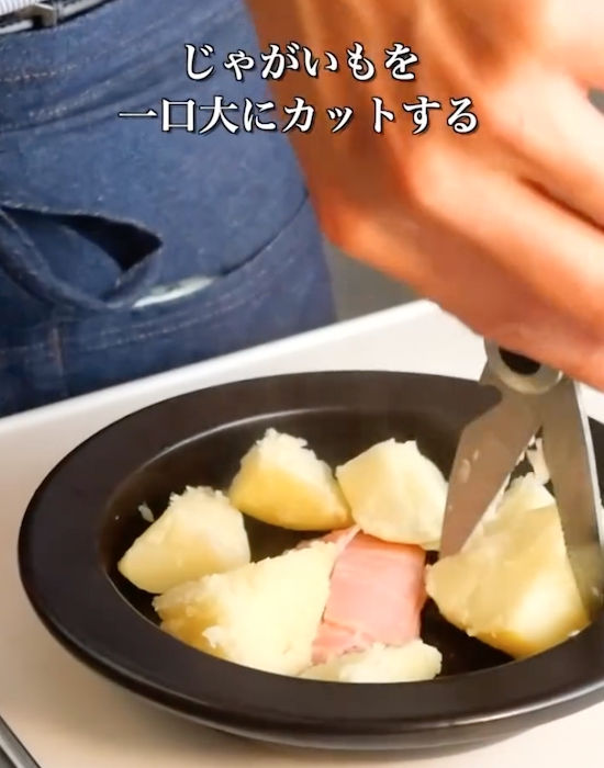 ベーコンの入った耐熱皿にカットしたジャガイモを入れる様子