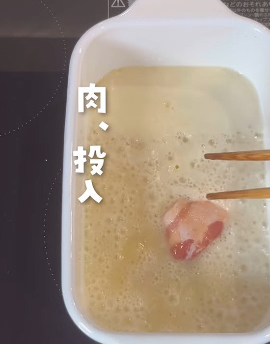 粉の入った油に豚肉を入れている様子