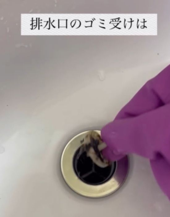 ゴム手袋を着用して洗面台のゴミ受けを取る様子