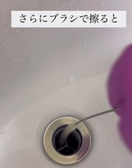 細長いブラシを排水口に入れて掃除をする様子