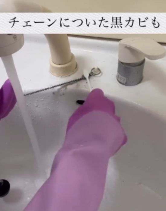 洗面台のチェーンを歯ブラシでこする様子
