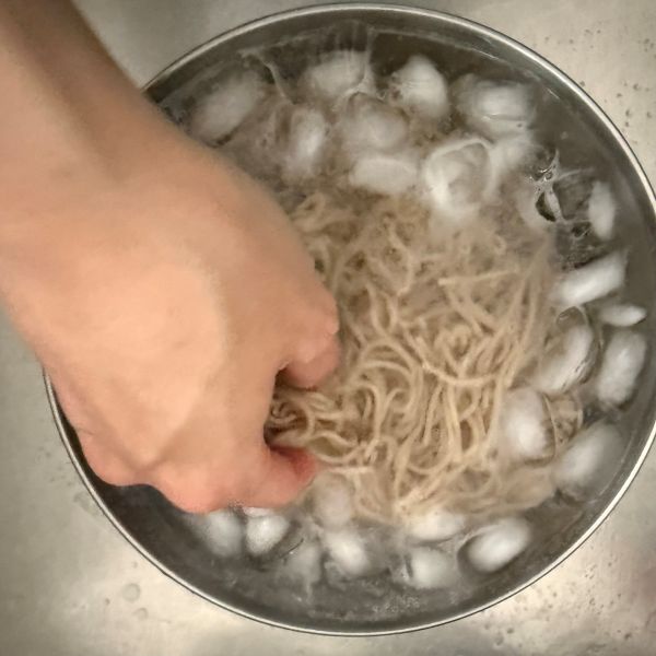 ゆでたそばを氷水に入れて洗う様子