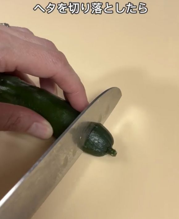 キュウリのツル側のへたを包丁で切る様子