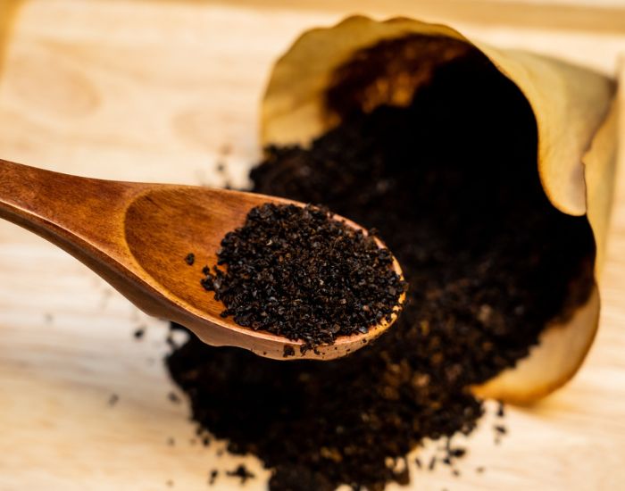 コーヒーフィルターに入ったコーヒーかすを木製スプーンですくった様子