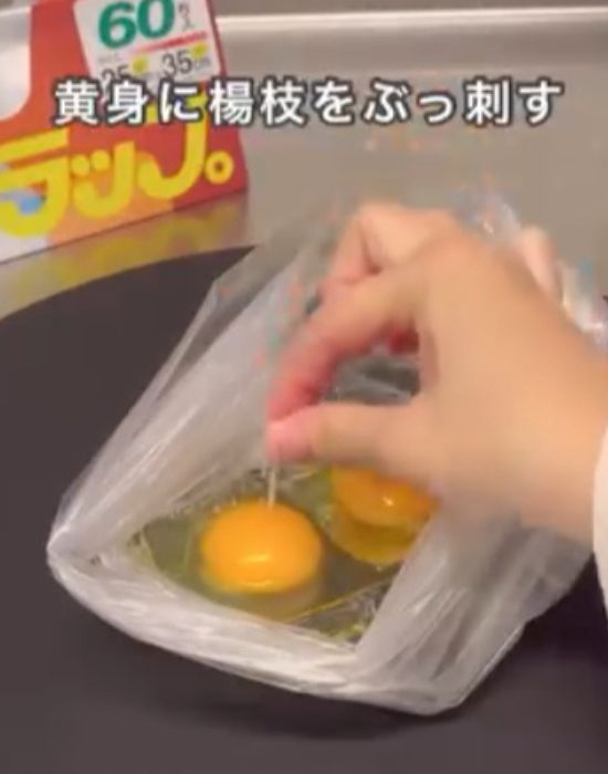 『アイラップ』に割り入れた卵の黄身につまようじで穴を開ける様子