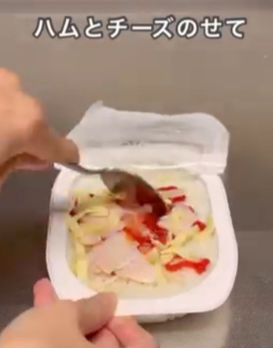 パックご飯にケチャップとハムとチーズをのせてスプーンで混ぜる様子