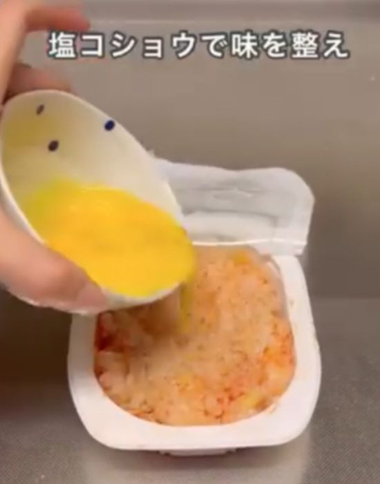 ケチャップを混ぜ合わせたパックご飯に溶き卵をかける様子