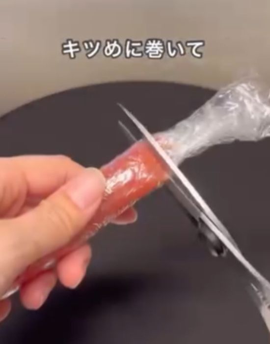 タラコを巻いたラップの端をはさみで切る様子