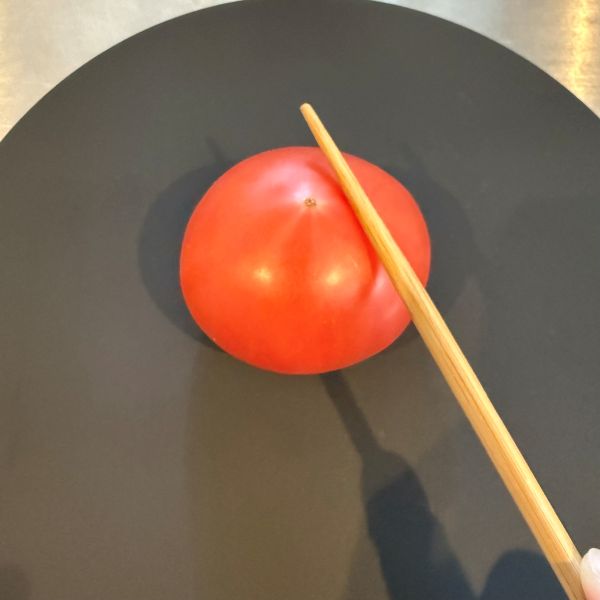 ヘタを下にしておいたトマトに箸を当てた様子