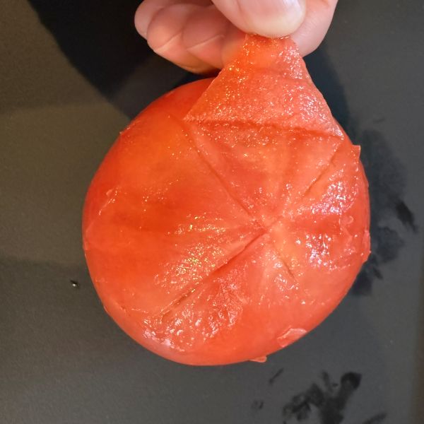 切り込みを入れた部分からトマトの皮をむく様子