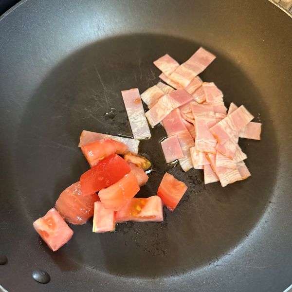 フライパンにカットしたトマトとベーコンを入れた様子