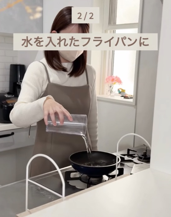 フライパンに水を入れる女性
