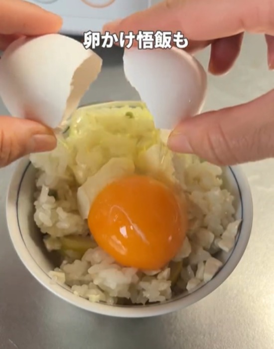 お茶碗に盛り付けたご飯に卵を割り入れる様子