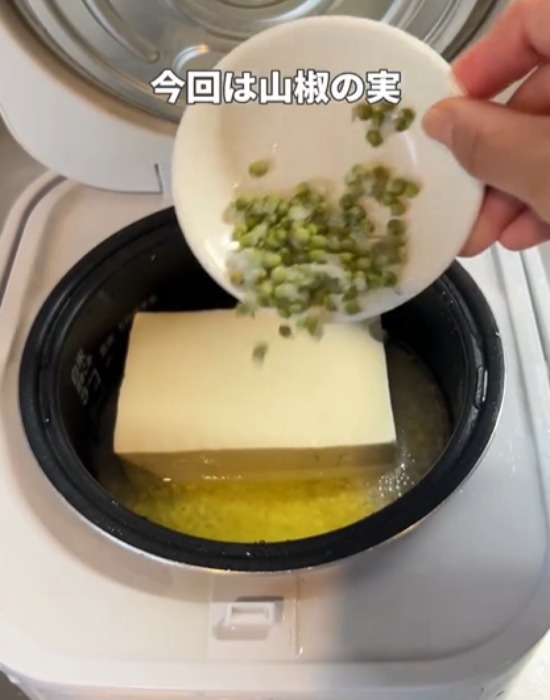 豆腐の上に山椒の実をかける様子