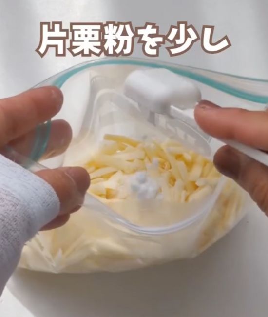 冷凍用の保存袋に移し替えたピザ用チーズの上に片栗粉を加える様子