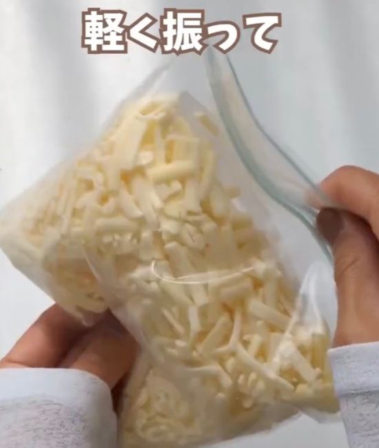 ピザ用チーズを入れた冷凍用の保存袋を軽く振る様子