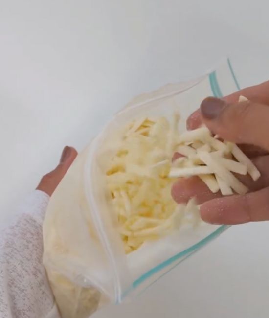 保存袋に入れて冷凍したピザ用チーズを指で触る様子