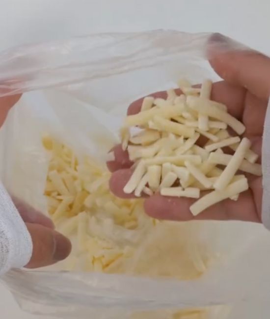『アイラップ』に入れて冷凍したピザ用チーズを手にのせた様子