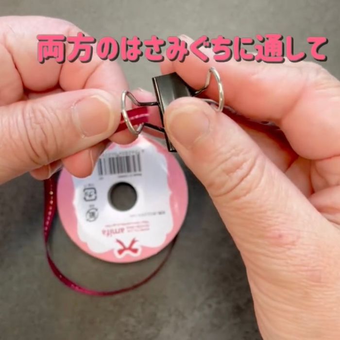 リボンの先端をダブルクリップのレバーに通す様子