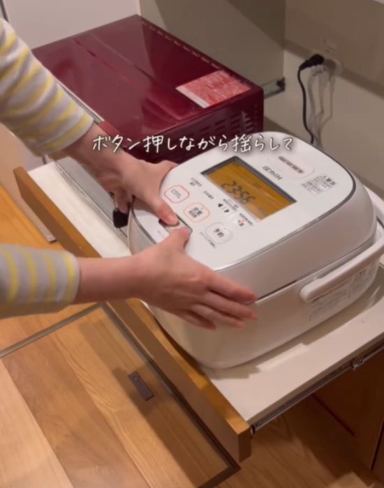 炊飯器のボタンを押しながら炊飯器を揺らす様子