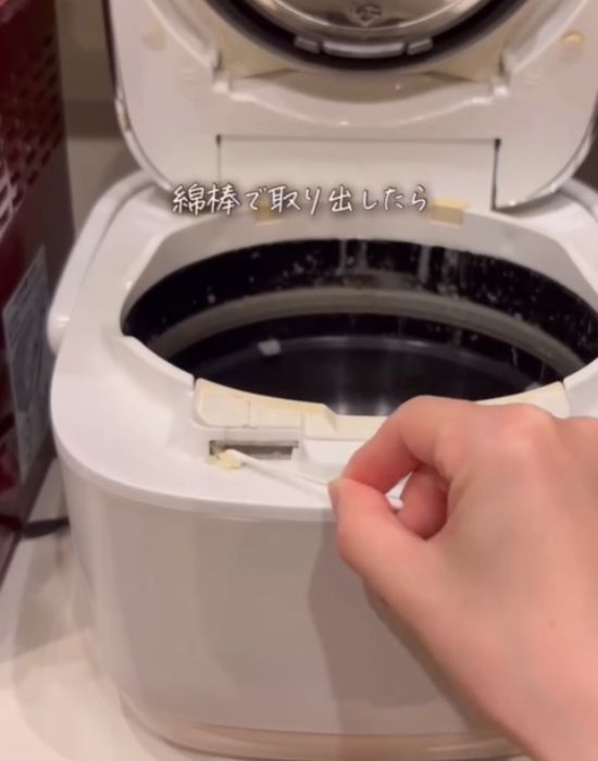 炊飯器の差し込み溝に入っているゴミを綿棒で取り出す様子