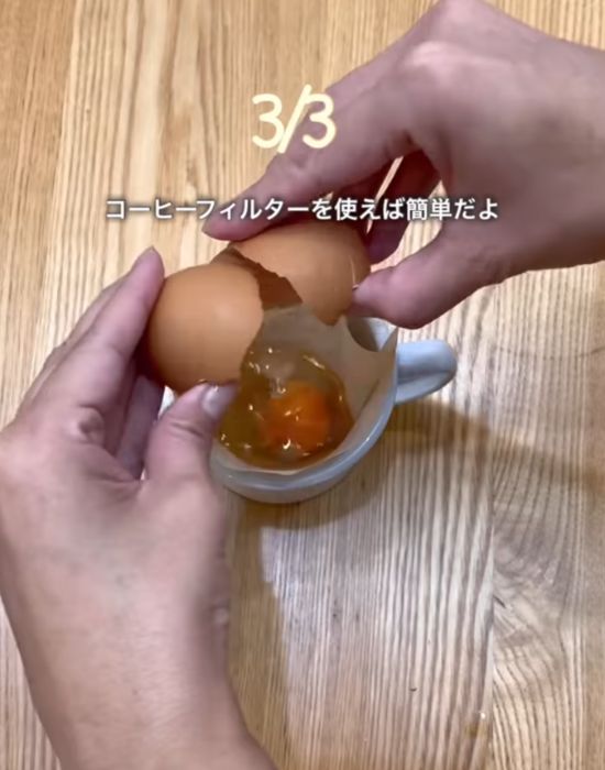 カップに入れたコーヒーフィルターに卵を割り入れる様子