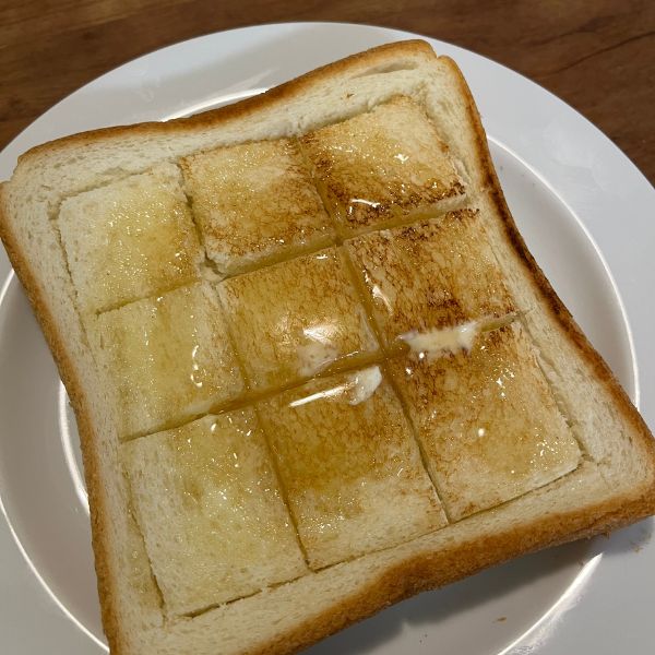 切り込みを入れた食パンにバターとハチミツを塗った様子