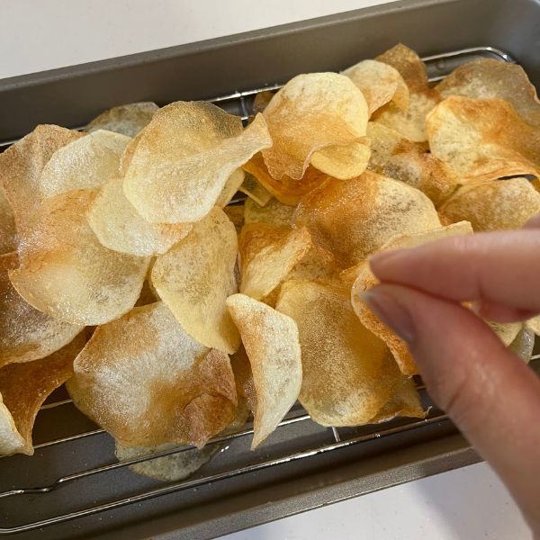 揚げたジャガイモに塩をまぶす様子