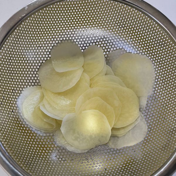 スライスしたジャガイモをザルにあげて水気を切る様子