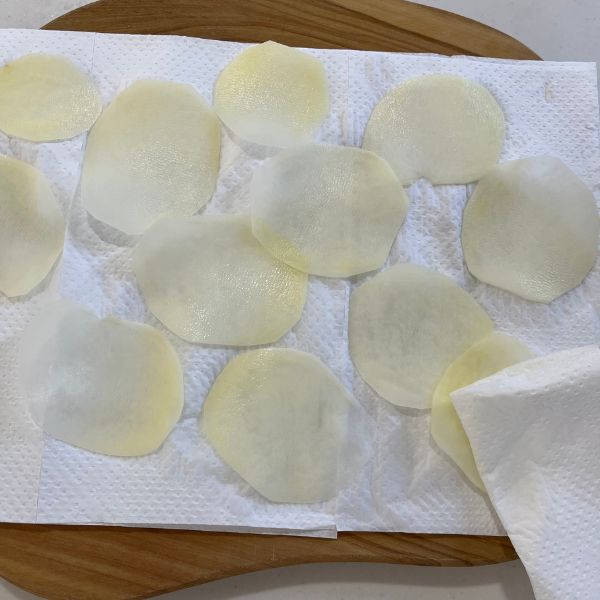 キッチンペーパーの上にスライスしたジャガイモ並べて水気を切る様子