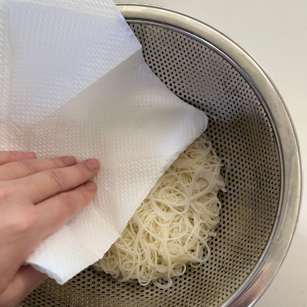 キッチンペーパーでザルにあげたそうめんの水分を取る様子