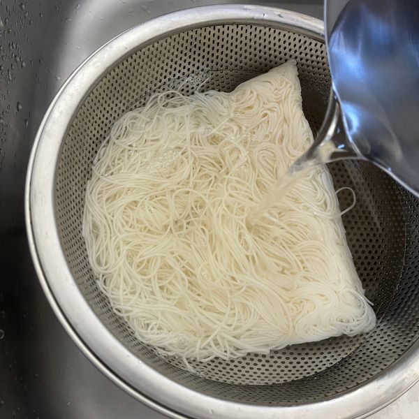冷凍したそうめんに熱湯をかけて解凍する様子