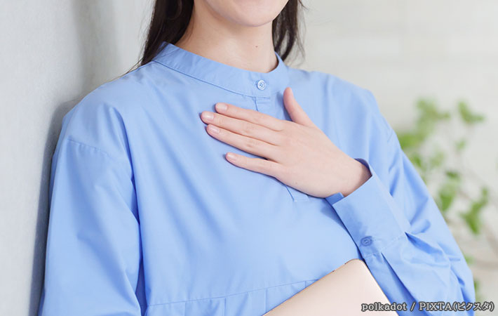 胸に手を当てる女性の写真