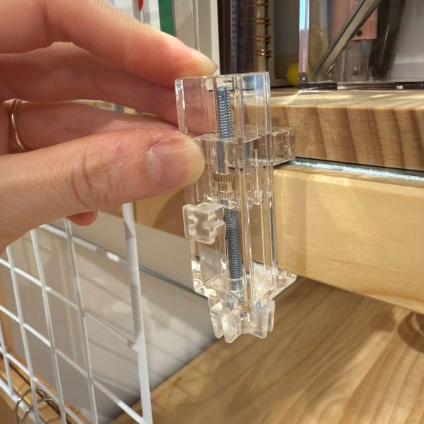 本体の下部にあるねじを緩めてかもいフックを取り付けたい場所にはめこむ様子