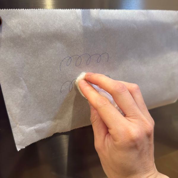 クッキングシートに書いた試し書きをぬらしたティッシュで拭く様子