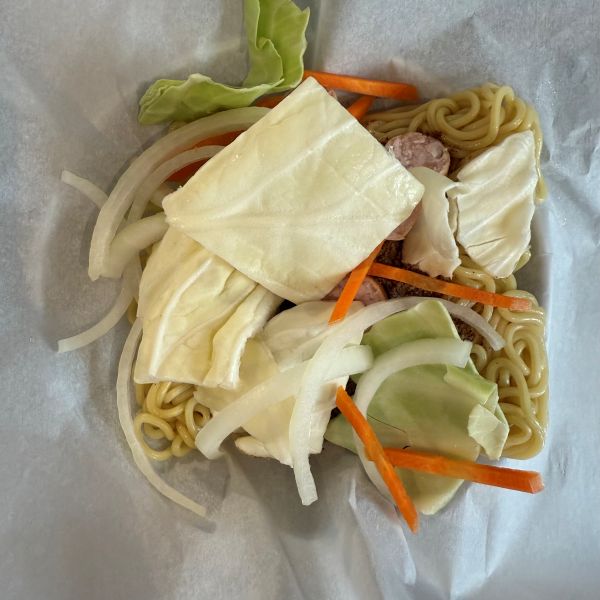 クッキングシートの上にのせた麺の上に野菜をのせた様子