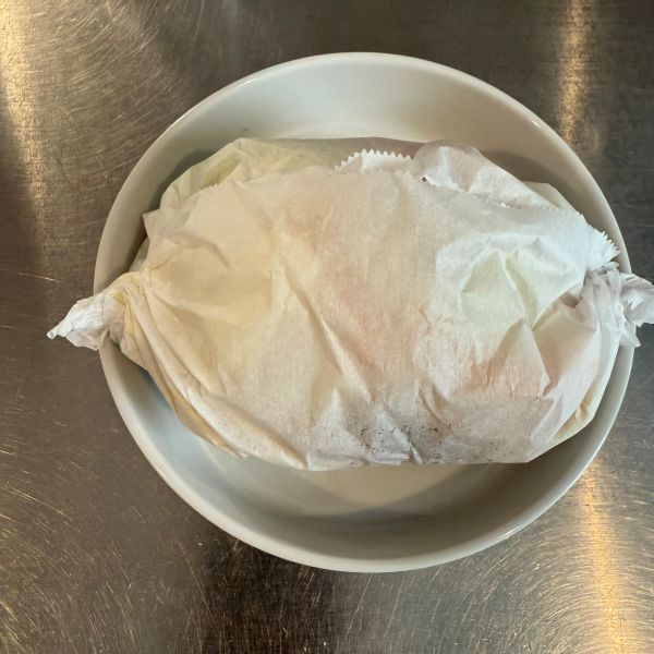 焼きそばの麺と具材をのせたクッキングシートの両端をねじって留めた様子