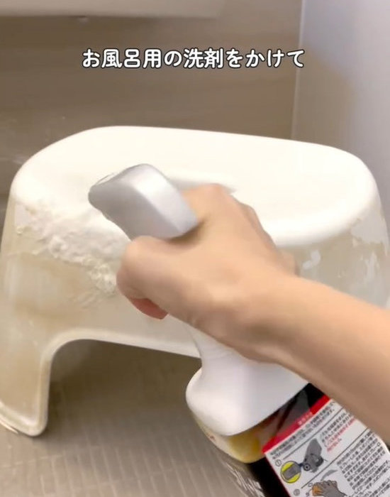 お風呂の椅子にウルトラハードクリーナーを吹きかけている様子