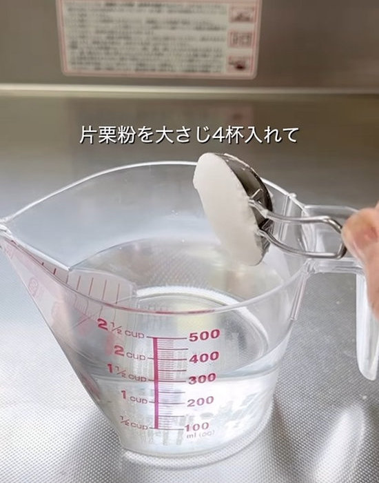 水の入った計量カップに片栗粉を入れている様子
