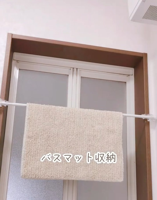 ダイソーのかもいフックと突っ張り棒にバスマットをかけている様子