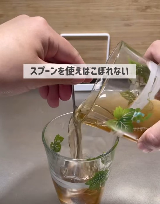 スプーンに沿わせてコップからコップに飲み物を移す様子