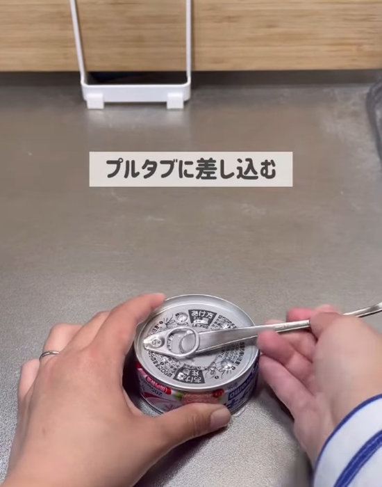 缶詰のプルタブにスプーンの柄を差し込む様子