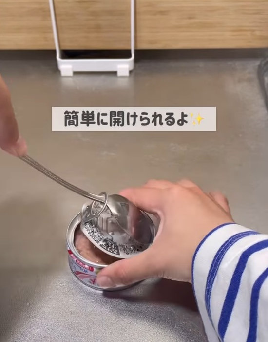 スプーンで缶詰のプルタブを開ける様子
