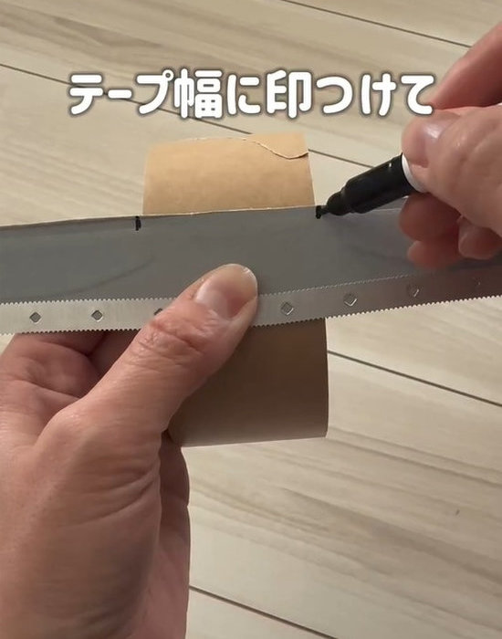 ラップのカッターをガムテープに当てペンで印を付ける様子