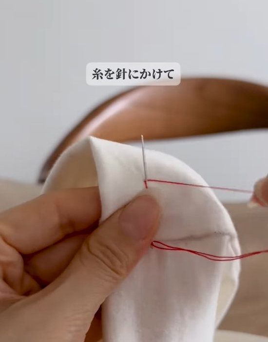 ズボンを縫った針に糸を巻き付けている様子