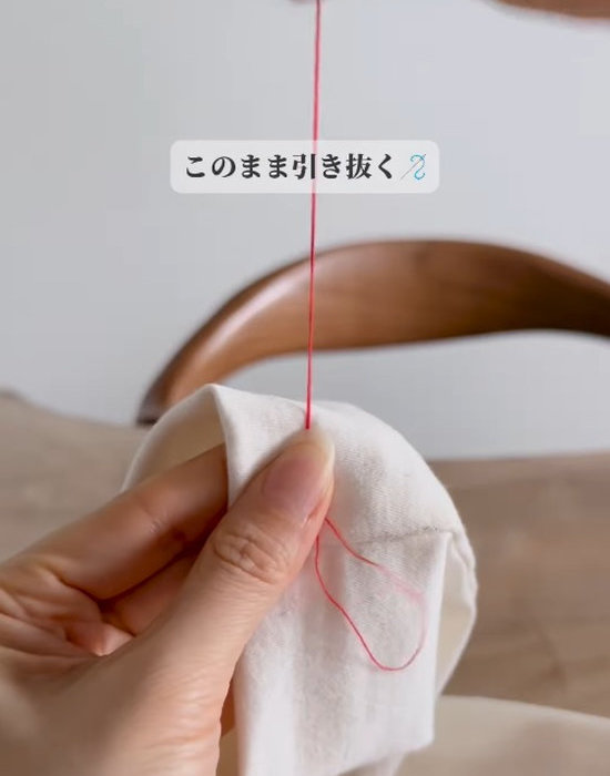 ズボンを縫った糸を引っ張っている様子